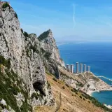 Widok na Gibraltar podczas wycieczki: skaliste zbocza, jaskinia, nowoczesne budynki i błękitne morze.