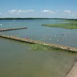 Letnie popołudnie w mieście nad jeziorem. Ludzie kąpią się i odpoczywają na drewnianych pomostach.