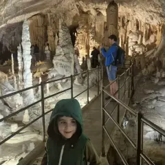 Dziecko w kapturze na ścieżce w jaskini Postojna, gdzie można kupić bilety. Widok na stalaktyty i stalagmity.