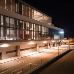 Nowoczesny terminal lotniska w nocy, z podświetlanymi oknami i drogami. Wygląda jak marzenie o podróży do Marbelli.