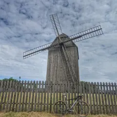 Wiatrak w Gorzowie Śląskim, obok drewnianego płotu stoi rower.