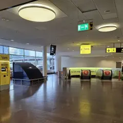 Na lotnisku w Sztokholmie, Arlanda Express, żółte automaty biletowe i ruchome schody czekają na podróżnych.