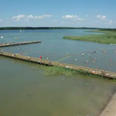 Letnie popołudnie w mieście nad jeziorem. Ludzie kąpią się i odpoczywają na drewnianych pomostach.