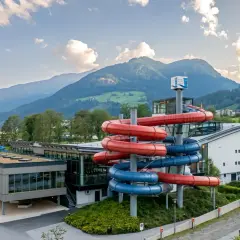 Wodne szaleństwo w Zillertal: kolorowe zjeżdżalnie wodne przyciągają do nowoczesnego aquaparku, w tle majestatyczne góry.