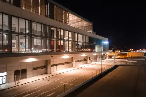 Nowoczesny terminal lotniska w nocy, z podświetlanymi oknami i drogami. Wygląda jak marzenie o podróży do Marbelli.