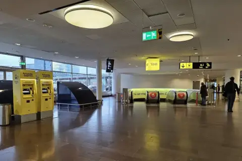 Na lotnisku w Sztokholmie, Arlanda Express, żółte automaty biletowe i ruchome schody czekają na podróżnych.