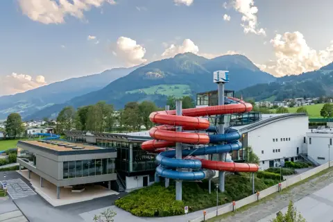 Wodne szaleństwo w Zillertal: kolorowe zjeżdżalnie wodne przyciągają do nowoczesnego aquaparku, w tle majestatyczne góry.