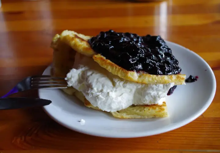 Puszyste naleśniki z bitą śmietaną i jagodami, idealne do menu chatki górzystów.