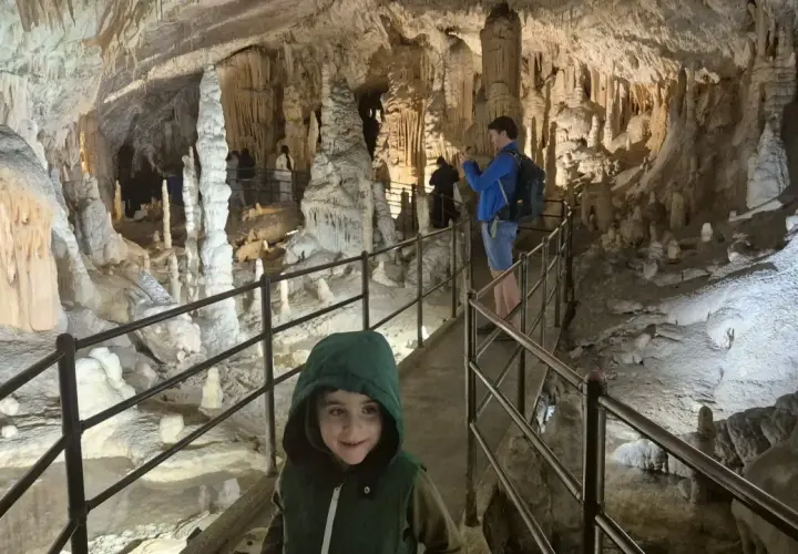 Dziecko w kapturze na ścieżce w jaskini Postojna, gdzie można kupić bilety. Widok na stalaktyty i stalagmity.