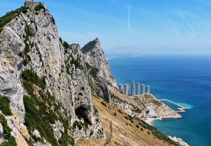 Widok na Gibraltar podczas wycieczki: skaliste zbocza, jaskinia, nowoczesne budynki i błękitne morze.