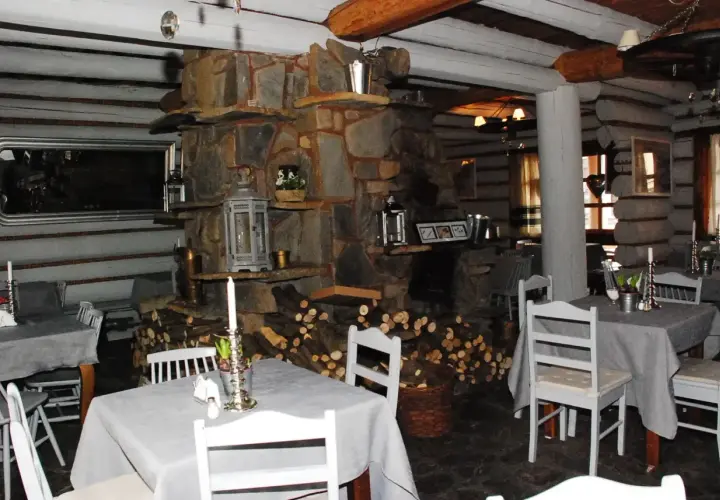 Przytulne bistro prosto z targu, z kamiennym kominkiem i drewnianymi belkami. Stoły nakryte szarymi obrusami, białe krzesła.