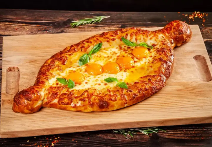 Chaczapuri adżarskie z rozpływającym się serem i jajkami, idealne na ucztę w restauracji gruzińskiej w Katowicach.