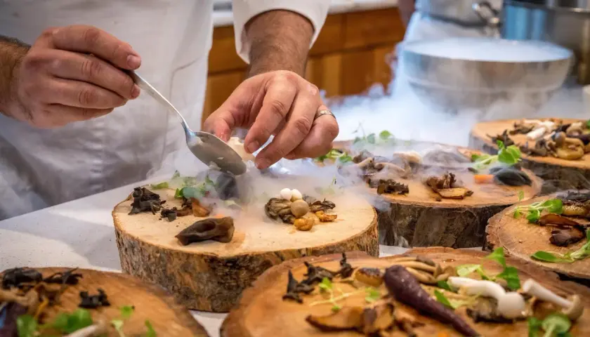 Szef kuchni serwuje danie z grzybami i mgłą, tworząc magiczną atmosferę w jednej z nietypowych restauracji w Warszawie.
