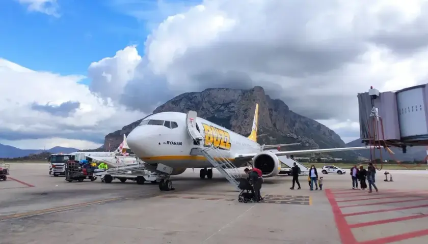 Samolot Buzz by Ryanair na lotnisku na Sycylii, z górami w tle.