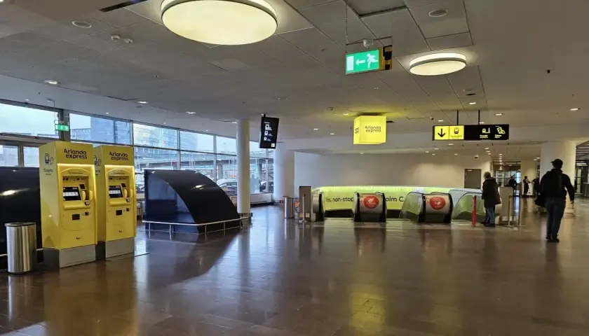 Na lotnisku w Sztokholmie, Arlanda Express, żółte automaty biletowe i ruchome schody czekają na podróżnych.
