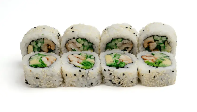 Rząd roladek sushi z ryżem, sezamem i kawałkami unagi, ogórka i awokado.