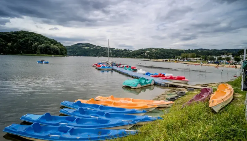 Jezioro Rożnowskie oferuje wiele atrakcji wodnych, w tym kolorowe rowerki wodne i kajaki czekające na plaży i przy pomoście.