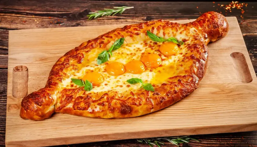Chaczapuri adżarskie z rozpływającym się serem i jajkami, idealne na ucztę w restauracji gruzińskiej w Katowicach.