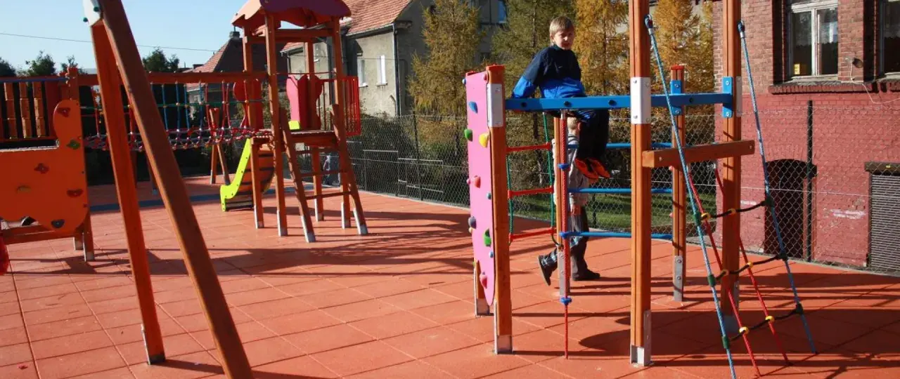 Plac zabaw w Przytkowicach z kolorowymi zjeżdżalniami i drabinkami. Dzieci bawią się na świeżym powietrzu.