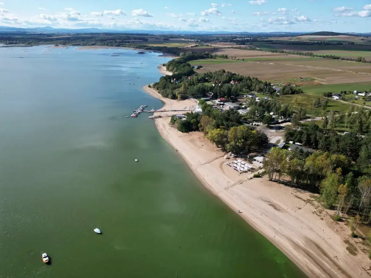 Malownicze jezioro Mietkowskie z piaszczystą plażą, mariną i zielonymi terenami rekreacyjnymi.