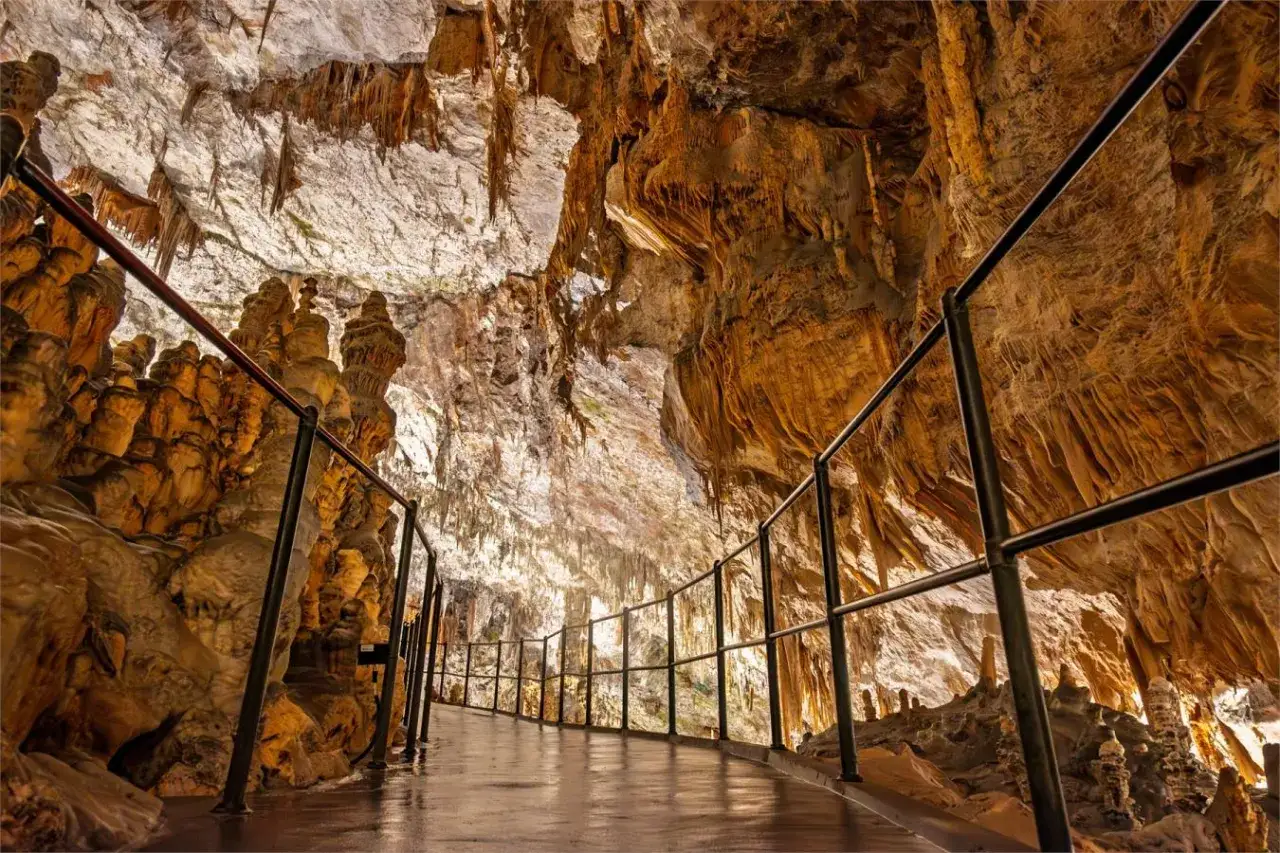 Ścieżka w jaskini Postojna, pełna stalaktytów i stalagmitów. Bilety do jaskini gwarantują niezapomniane wrażenia.