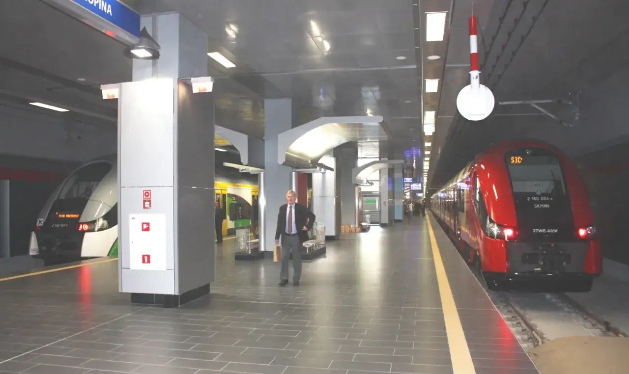 Warszawa Centralna Lotnisko Chopina: czerwony pociąg SKM i biało-zielony skład na peronie.